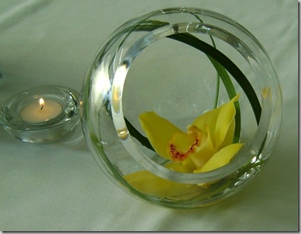 yellow orchids in simple glass vases with a candle