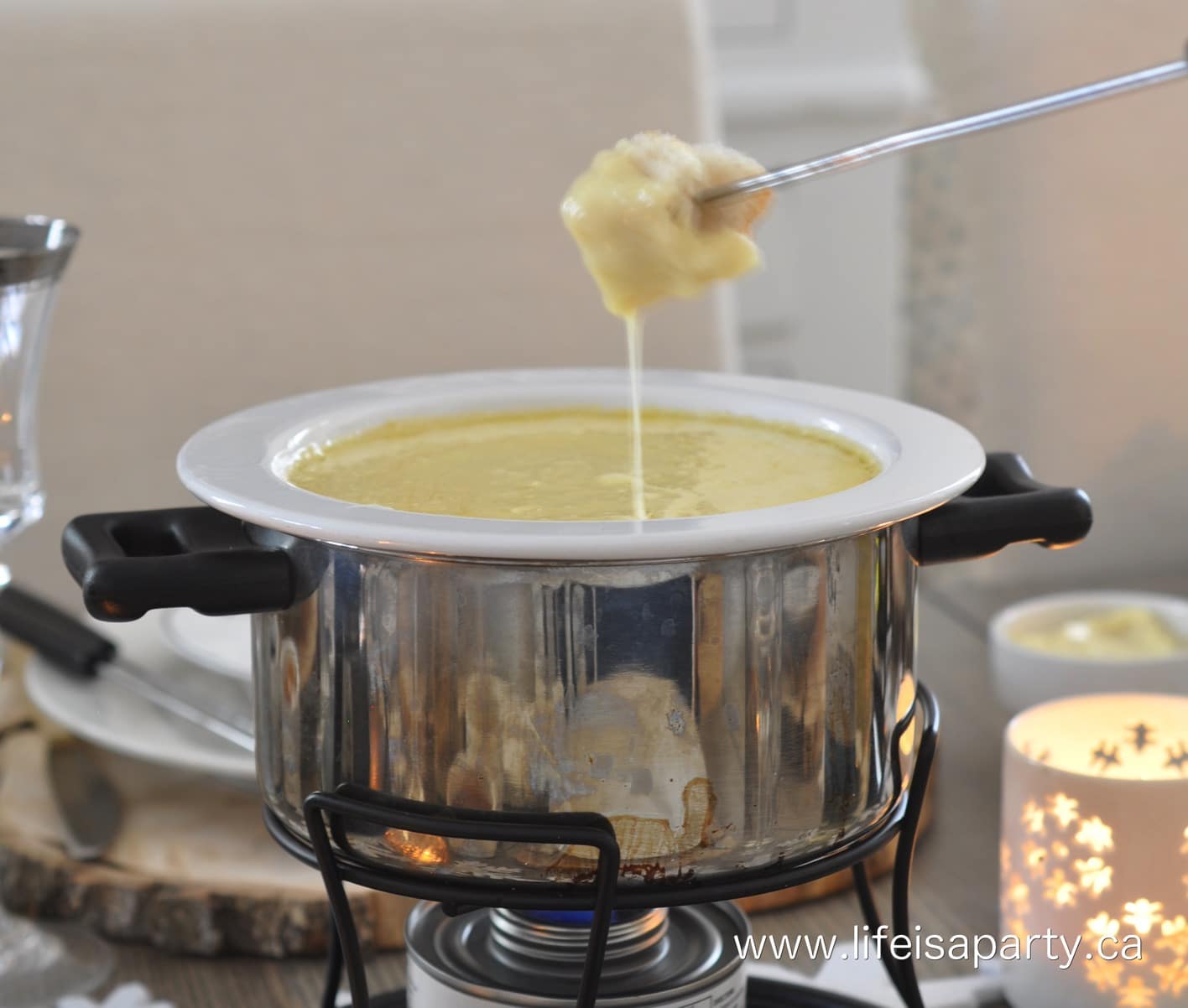Cheese fondue pot with a piece of bread dipping in and dripping cheese.