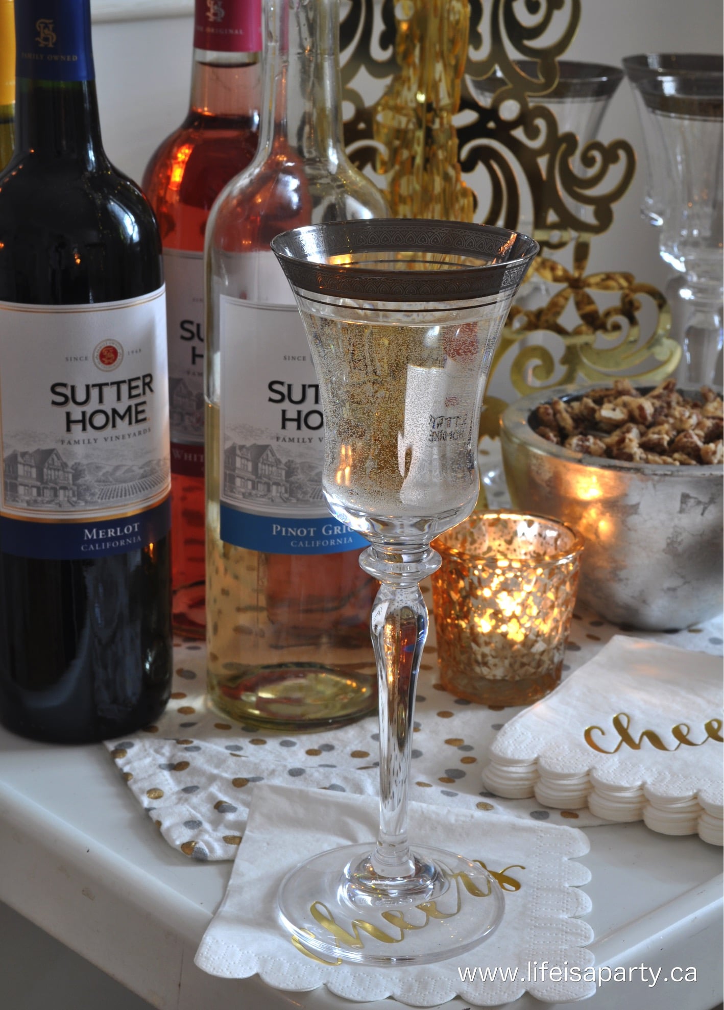 Wine glass with a silver rim, and wine bottles on a bar cart.