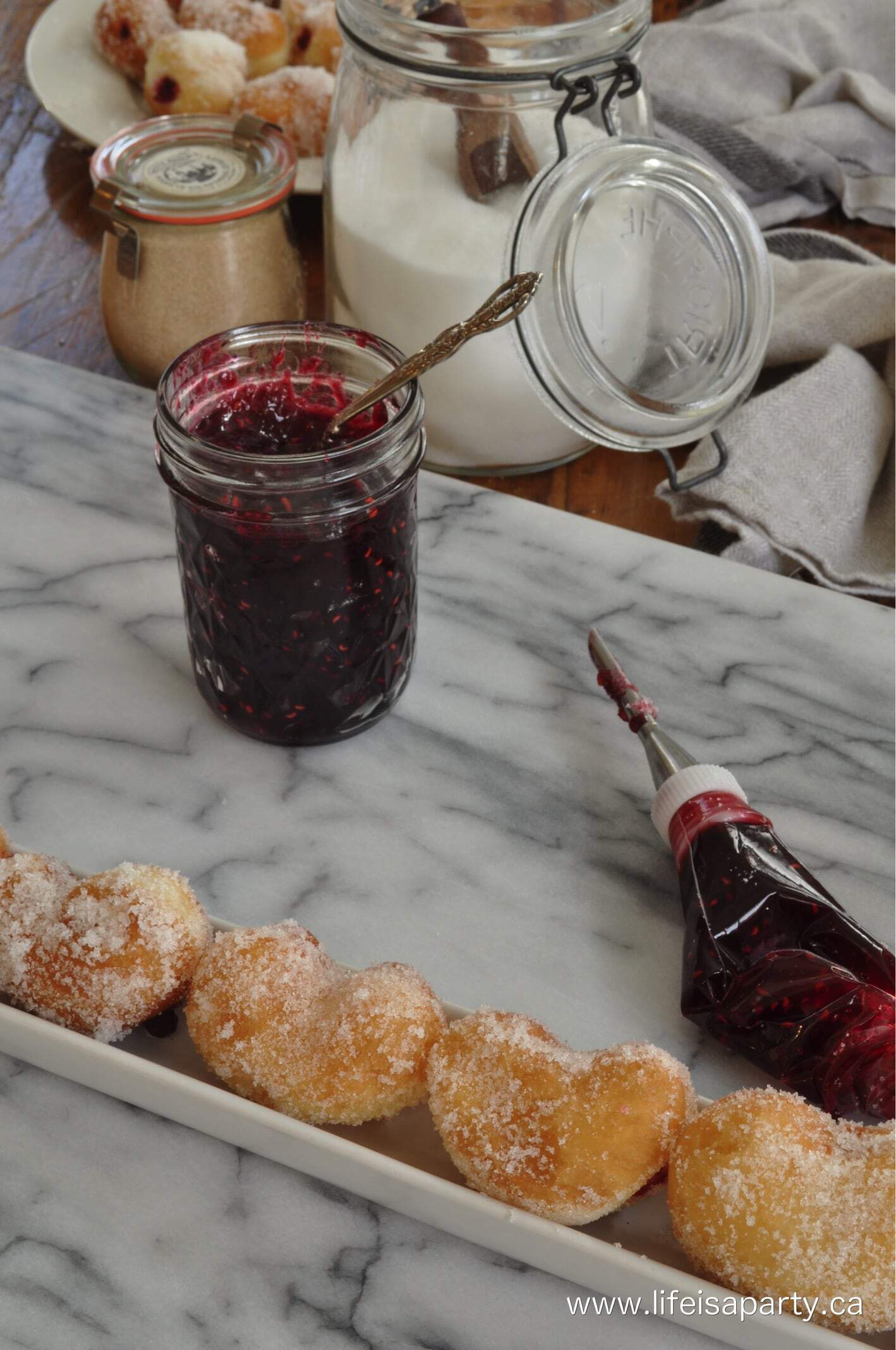 heart shaped mini donuts getting filled with raspberry jam