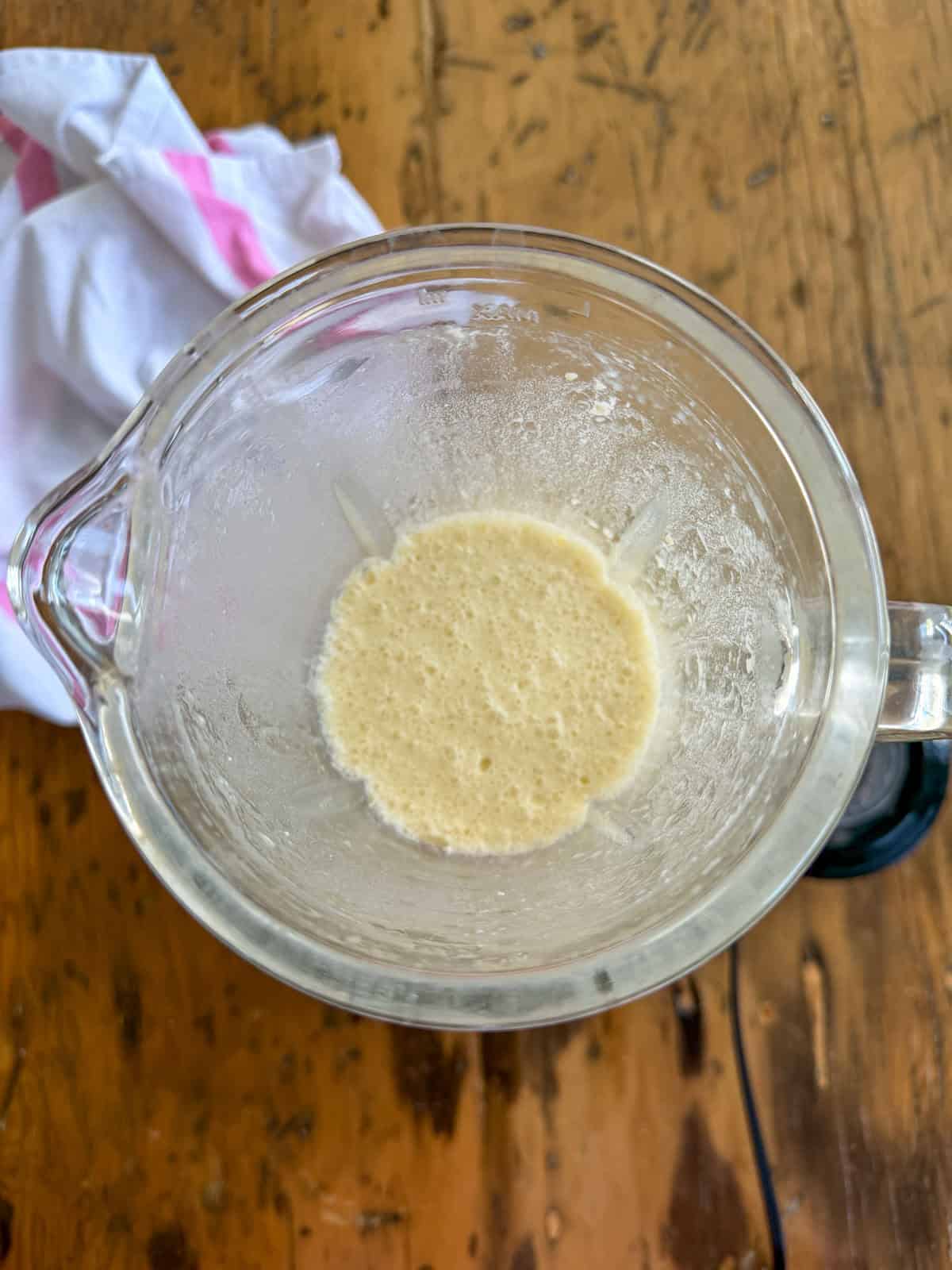 Freshly blended sweet crepe batter in a glass blender jar with a smooth, frothy surface.
