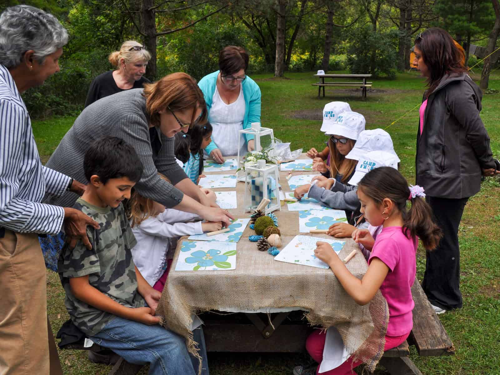 Children decorating placemats at a craft table during a camping birthday party.