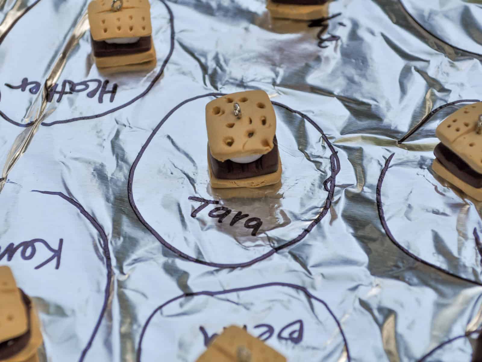 Close up of a handmade polymer clay s'more charm with a jump ring and name label.