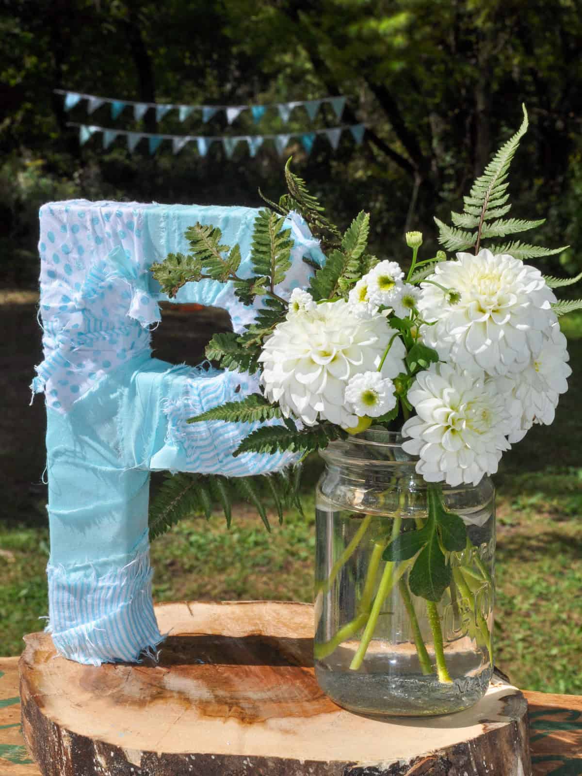 Fabric wrapped letter P decoration next to white dahlias in a mason jar.