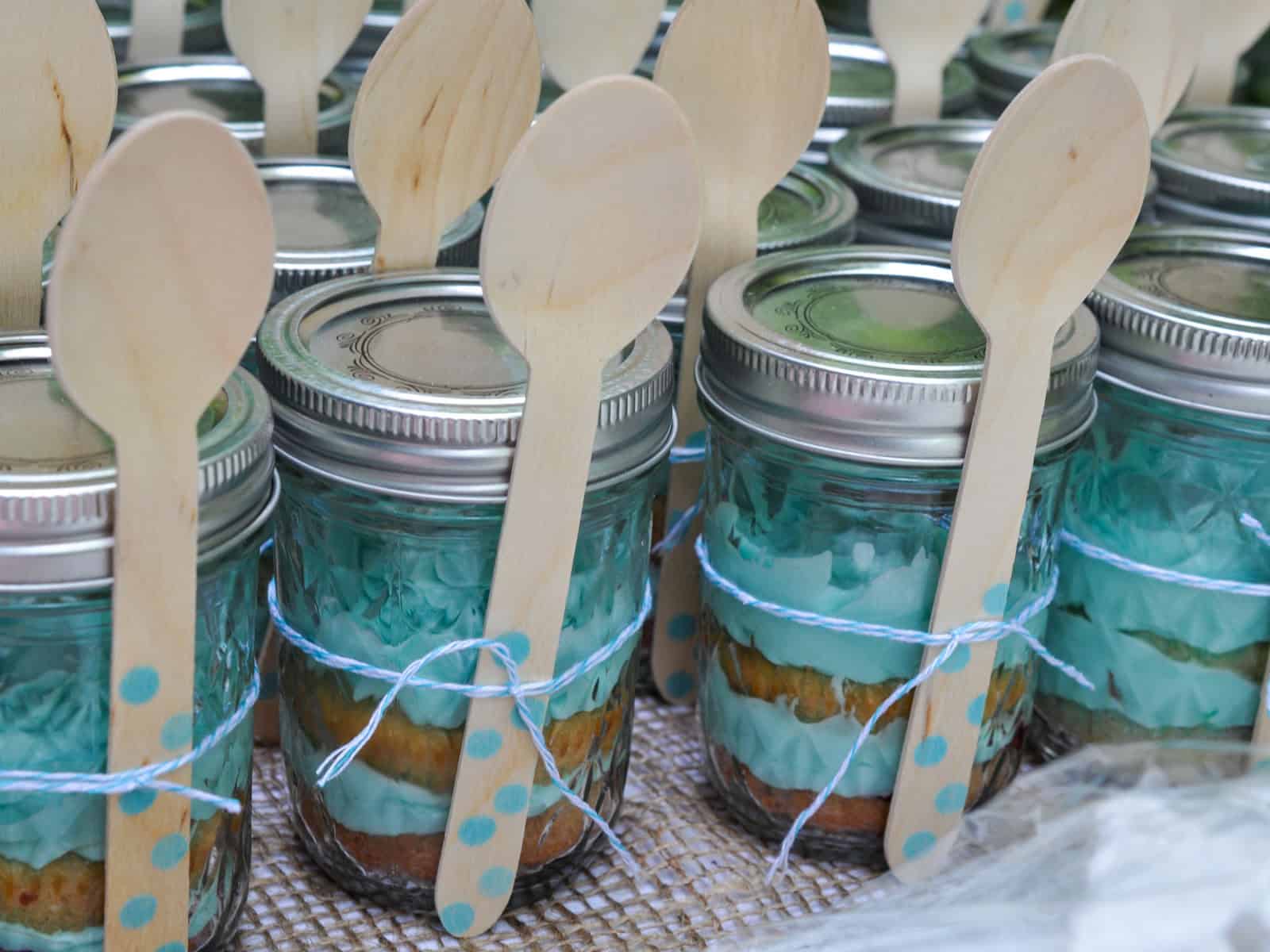Cupcakes in mason jars tied with baker's twine and polka dot wooden spoons.