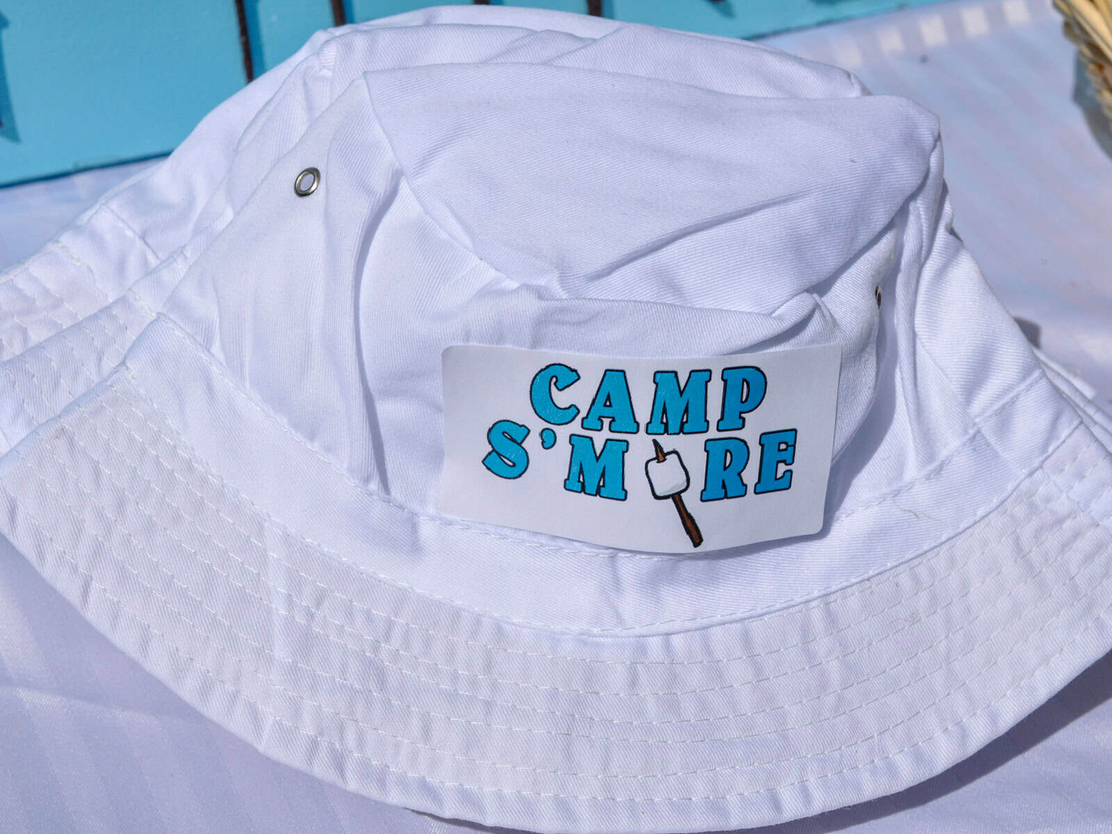 White bucket hat with a Camp S'more logo sticker used as a party favor.