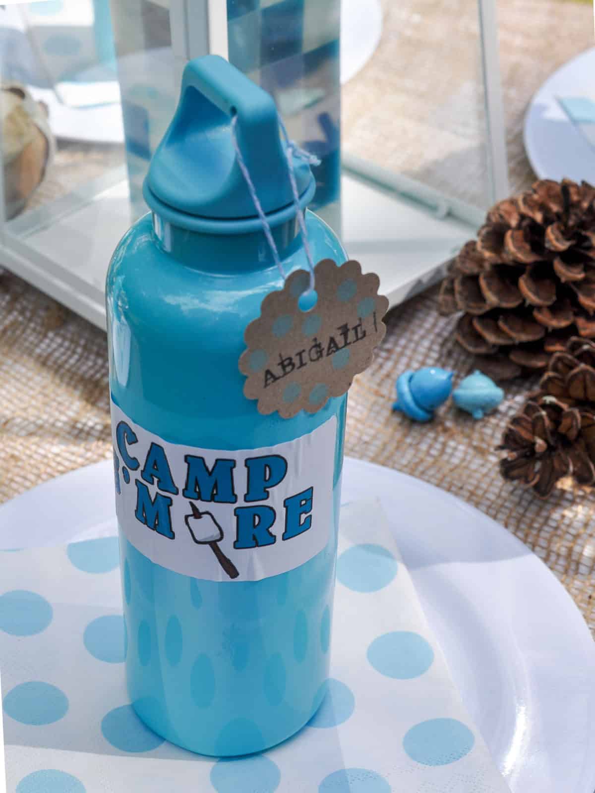 Personalized aqua water bottle with a Camp S'more label and a name tag for a party guest.