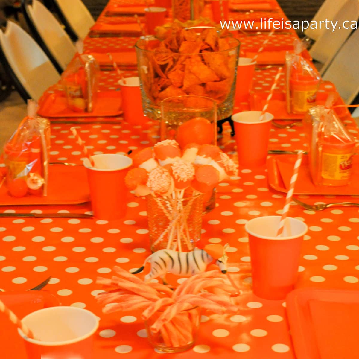 Orange theme party table with orange decor and foods.