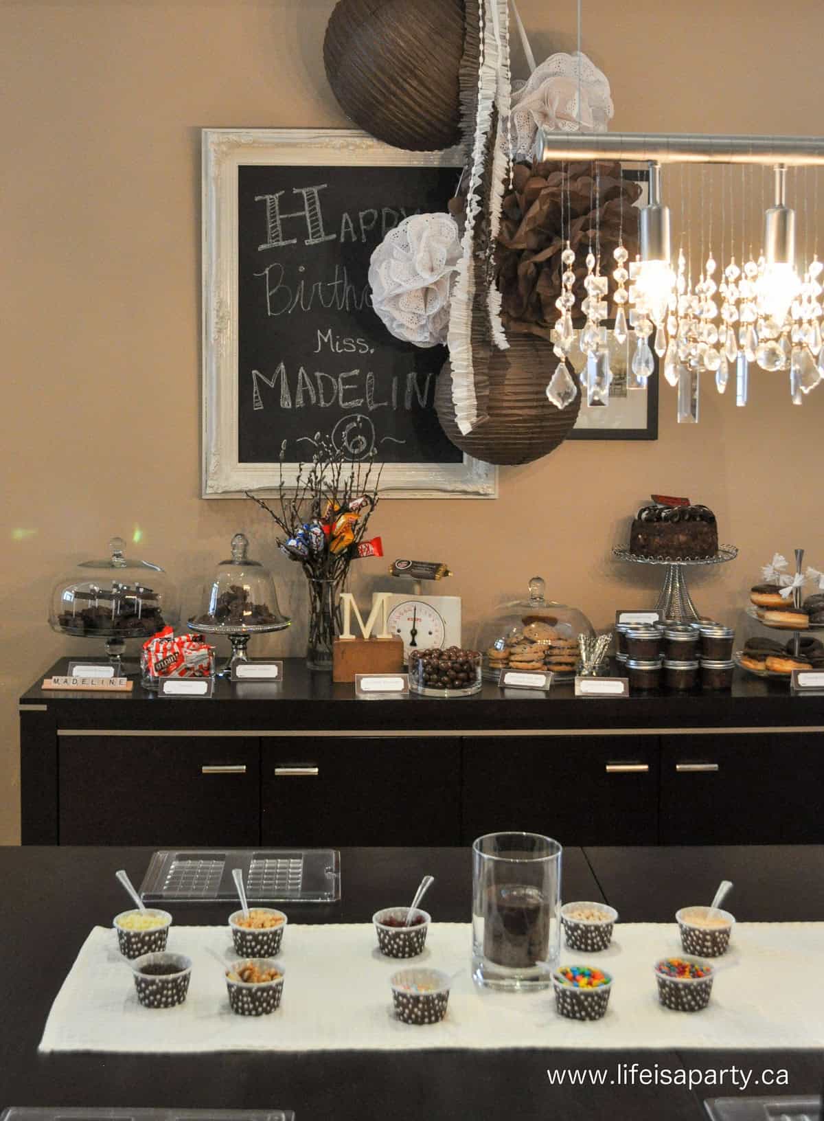 Make your own chocolate bar activity set up with chocolate dessert table in the background.