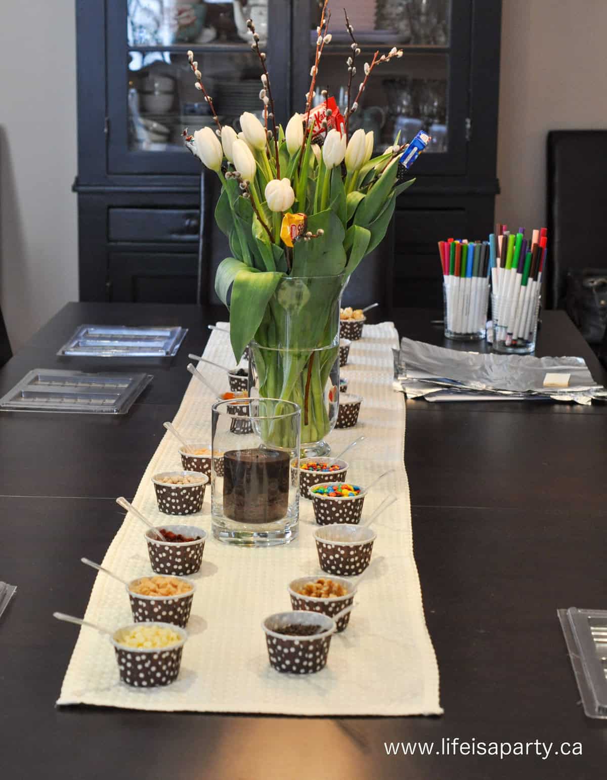 Table with make your own chocolate bar ingredients in small brown polka dot cups.