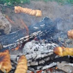 Campfire cinnamon rolls being roasted over a campfire.