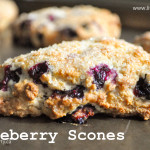Freshly baked blueberry scones made with fresh blueberries and topped with coarse sugar on a baking tray.