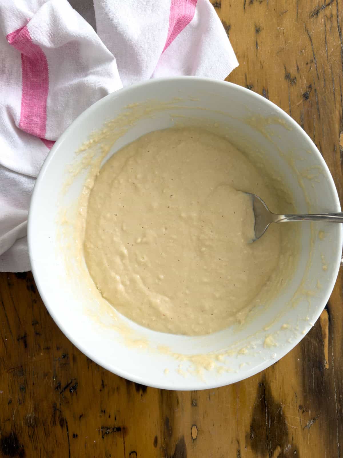 Smooth funnel cake batter combined in a white bowl ready for frying.