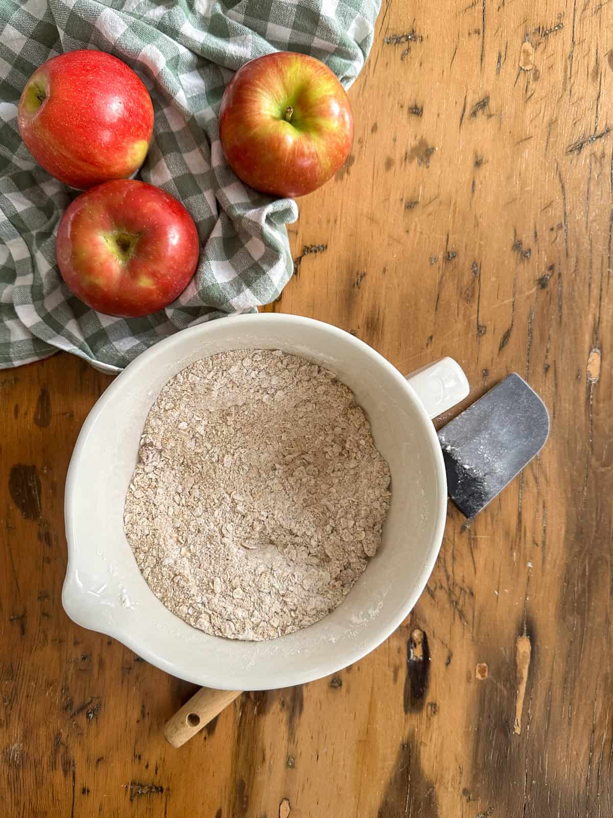 Dry ingredients for apple crisp topping in a mixing bowl beside some apples.