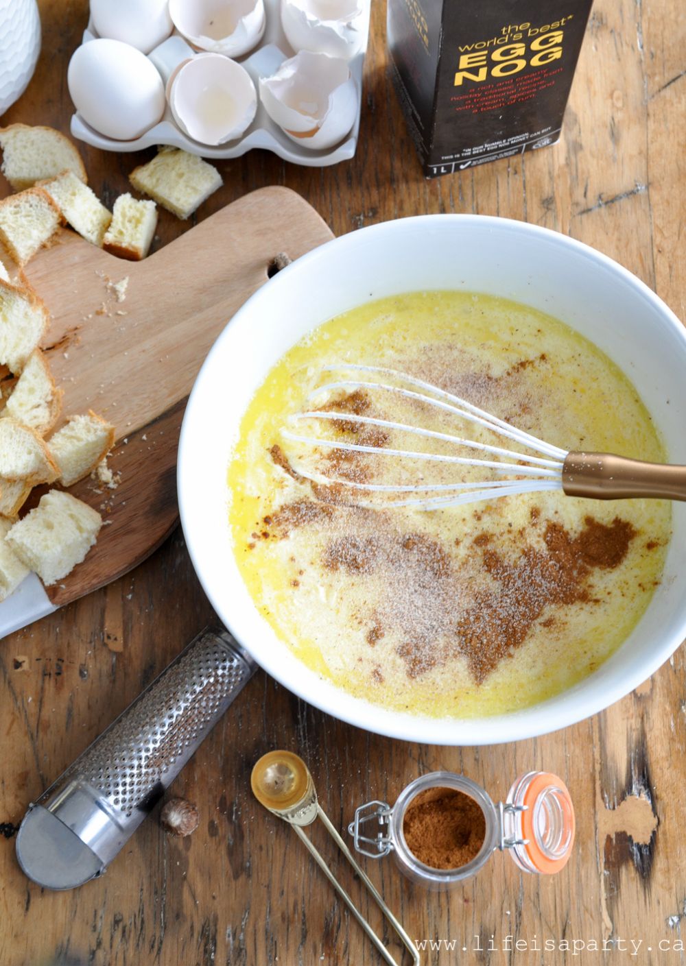 Making eggnog custard for eggnog bread pudding in a bowl, with nutmeg and cinnamon.