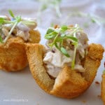 Chicken salad in a toast cup with onion sprout garnish.