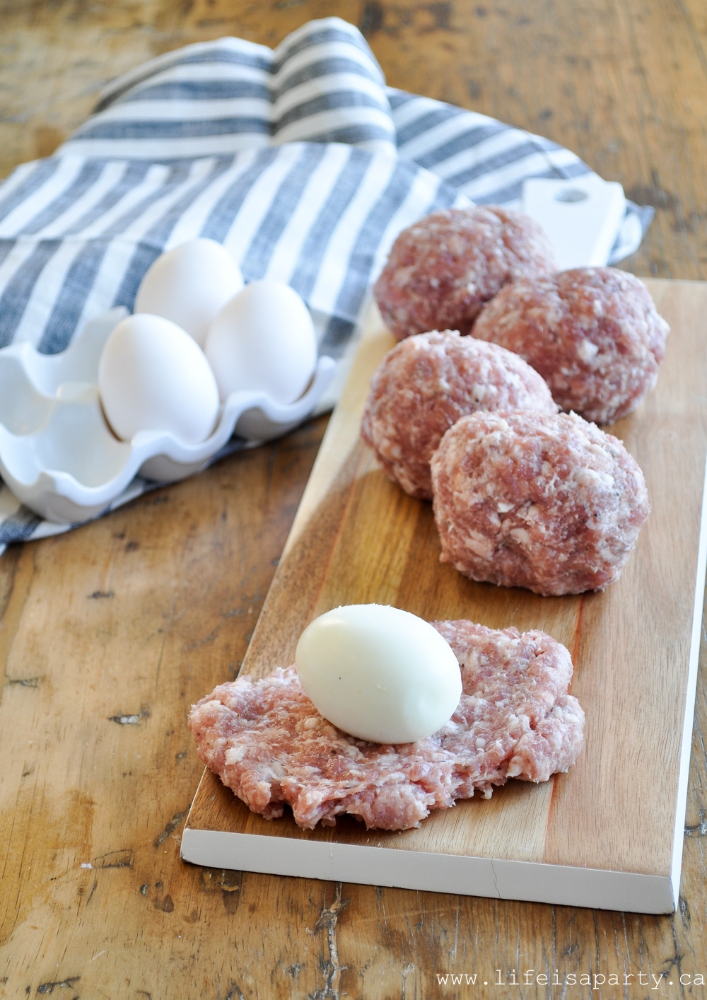 wrapping a hard boiled egg in sausage to make scotch eggs