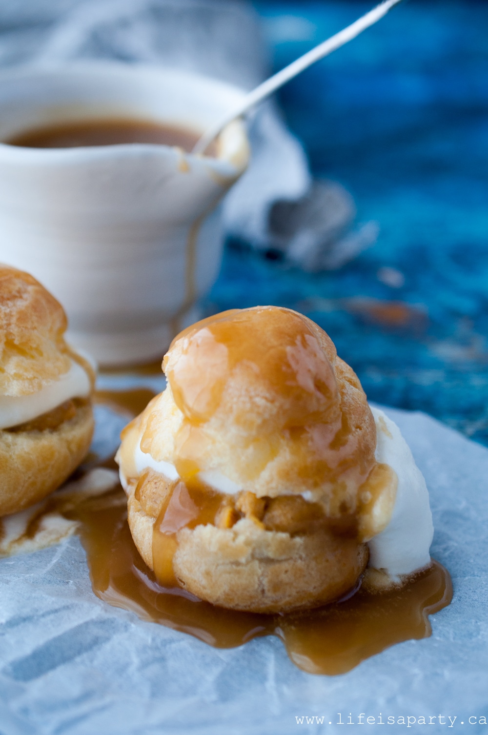 Pumpkin Cream Puffs: A cream puff filled with pumpkin pastry cream, whipped cream, and topped with warm caramel sauce for the perfect fall dessert.