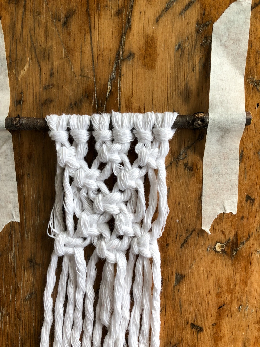 mini square knot macrame piece taped to a table