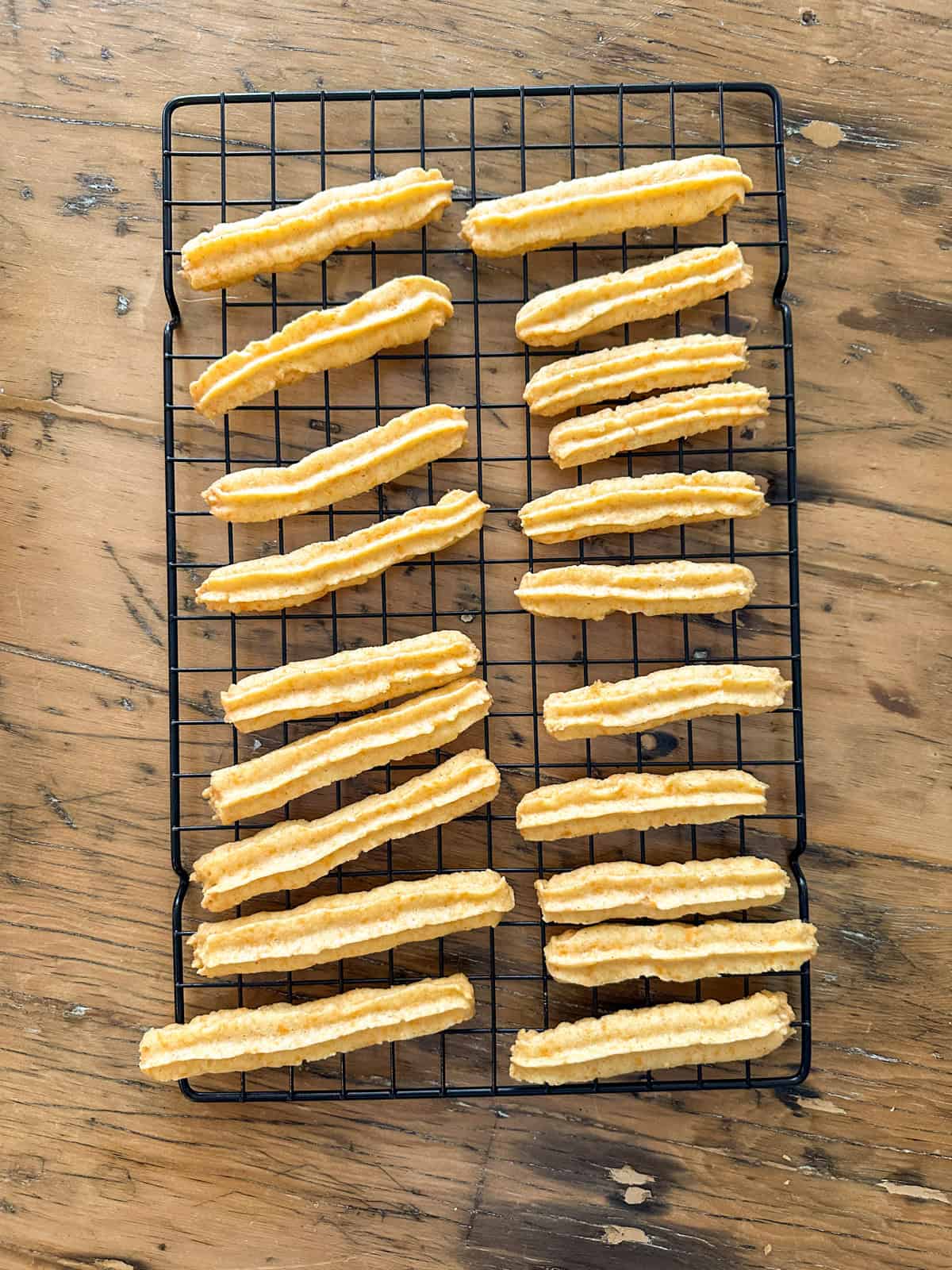 Baked homemade cheese straws cooling on a wire rack.