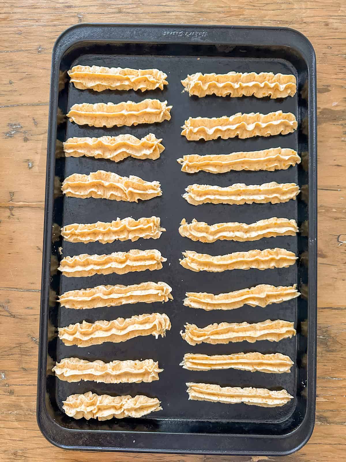 Cheese straws piped onto a cookie sheet ready to be baked.