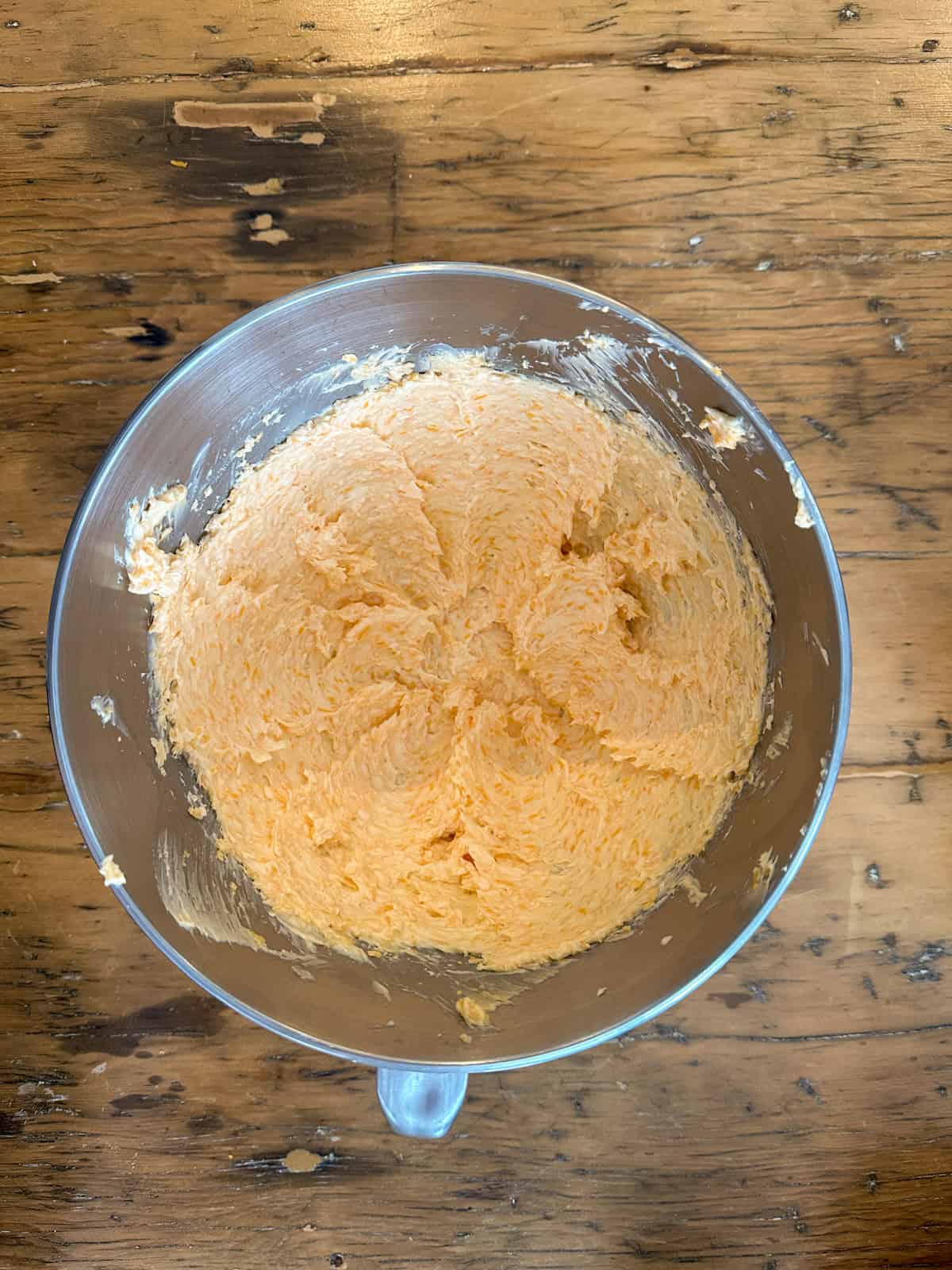 Sharp cheddar and butter fully combined in the bowl of a stand mixer.