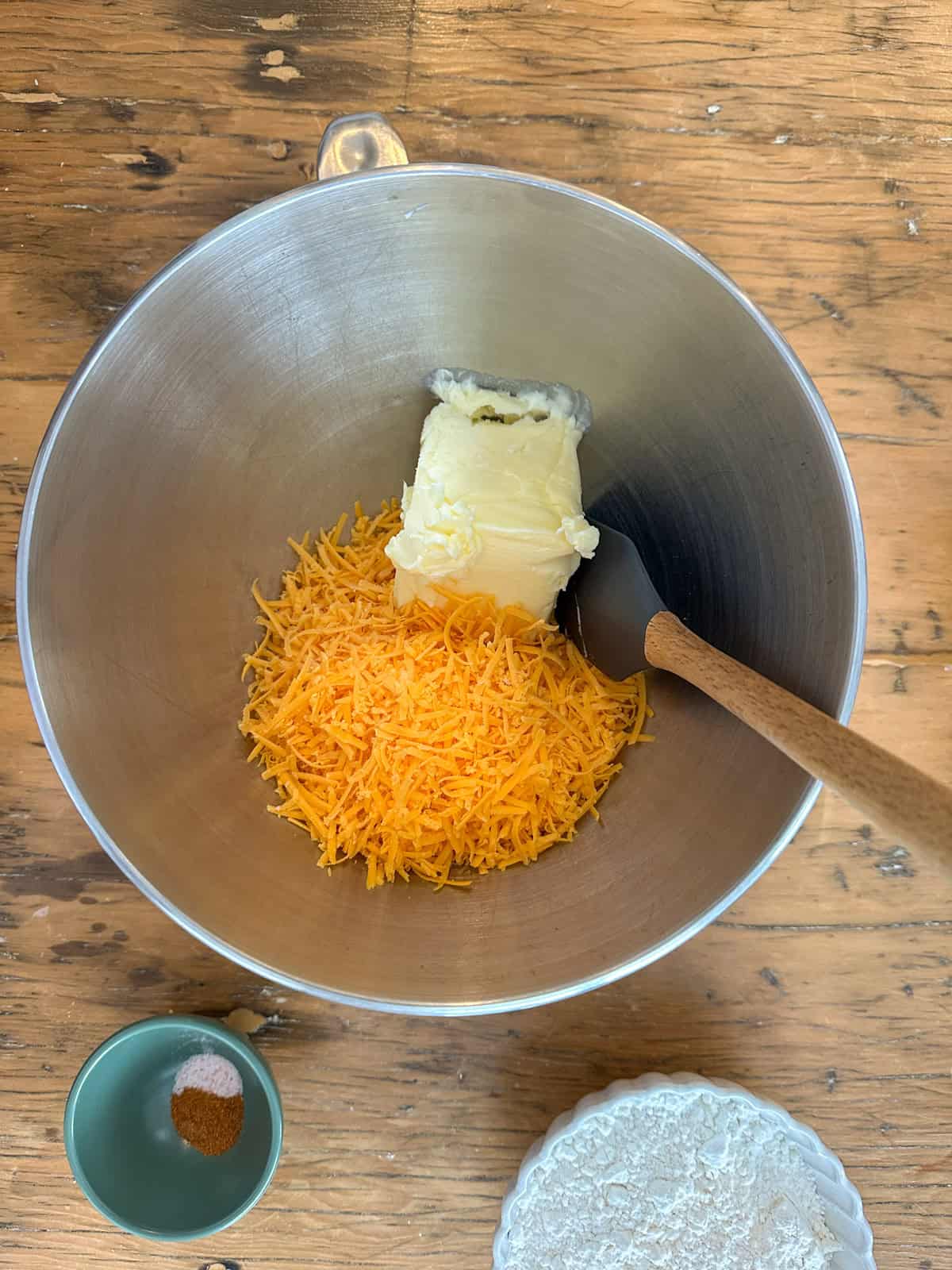 Finely grated sharp cheddar cheese and butter in a stand mixer bowl.