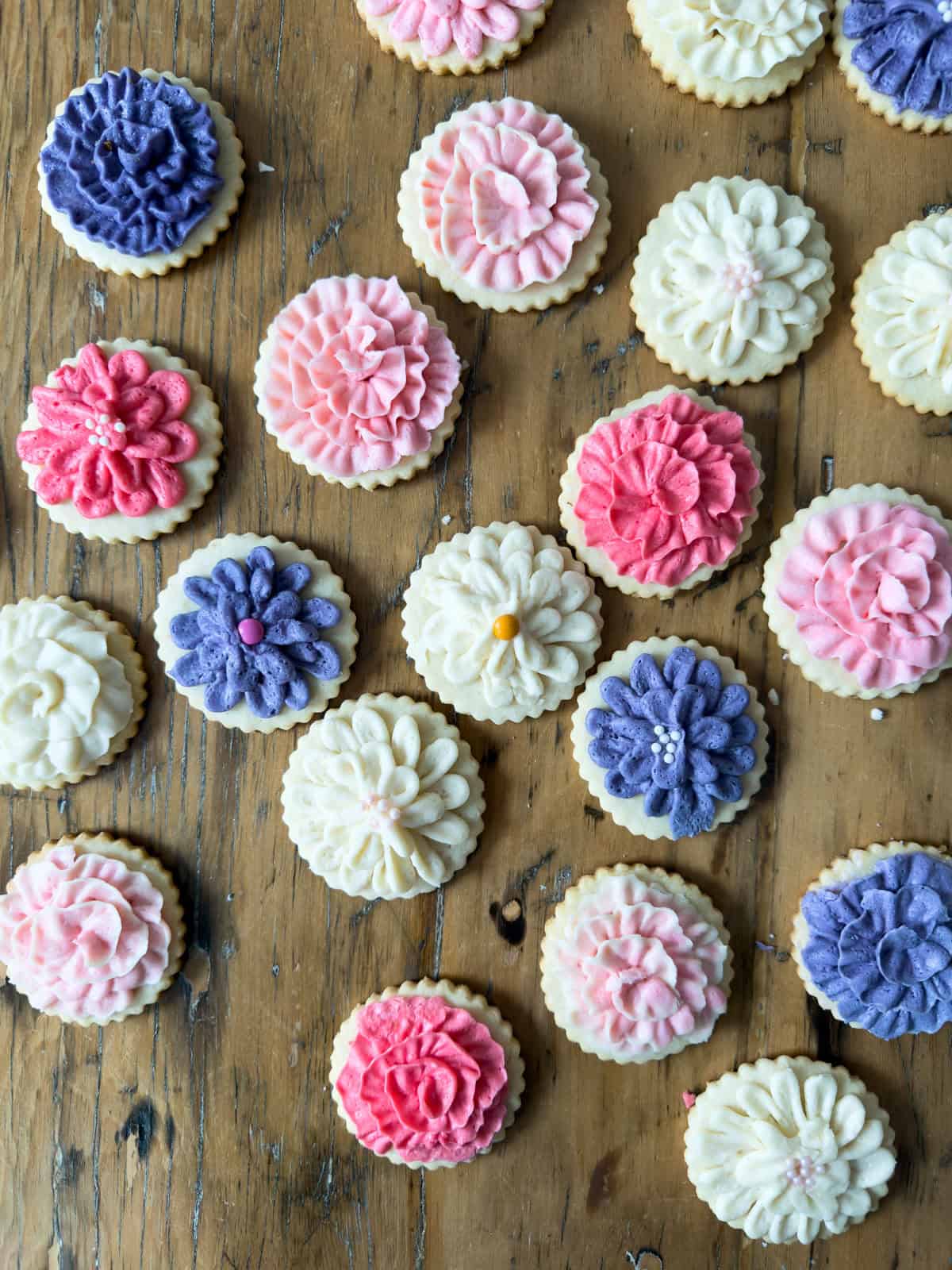 Cut out butter cookies with pink lavender and cream flower buttercream decorating overhead.