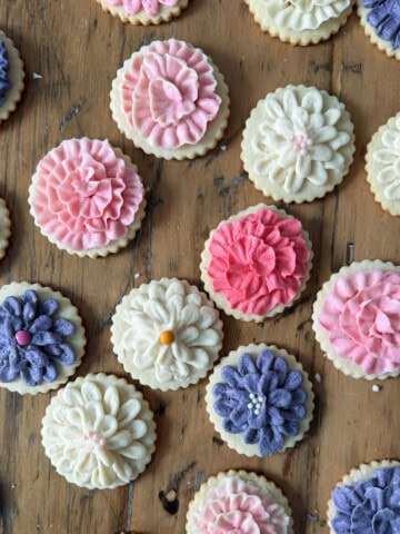 Cut out butter cookies decorated with pink purple and cream flower buttercream.