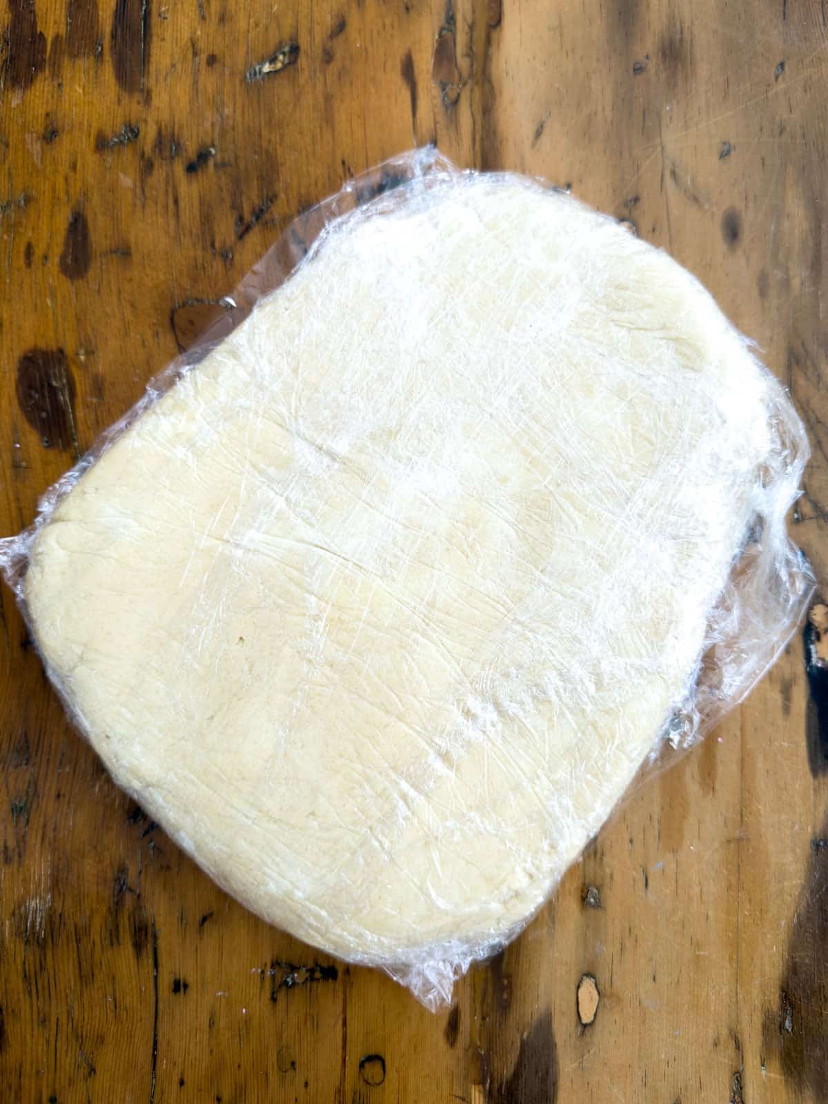 Cut out butter cookie dough shaped into disk wrapped in plastic wrap for chilling.