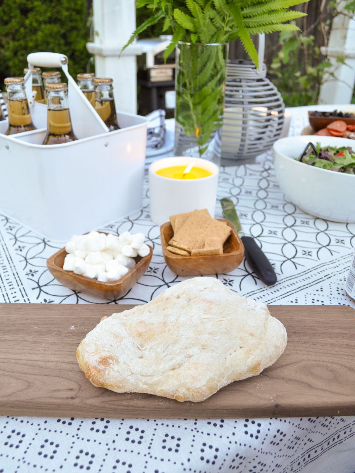 Baked pizza crust cooling on a wood board before adding s'mores toppings.