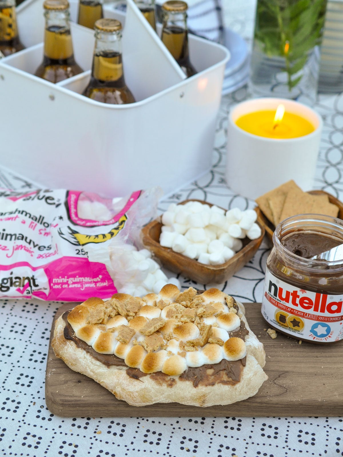 Finished s'mores pizza with toasted marshmallows and graham cracker pieces on a wood board.