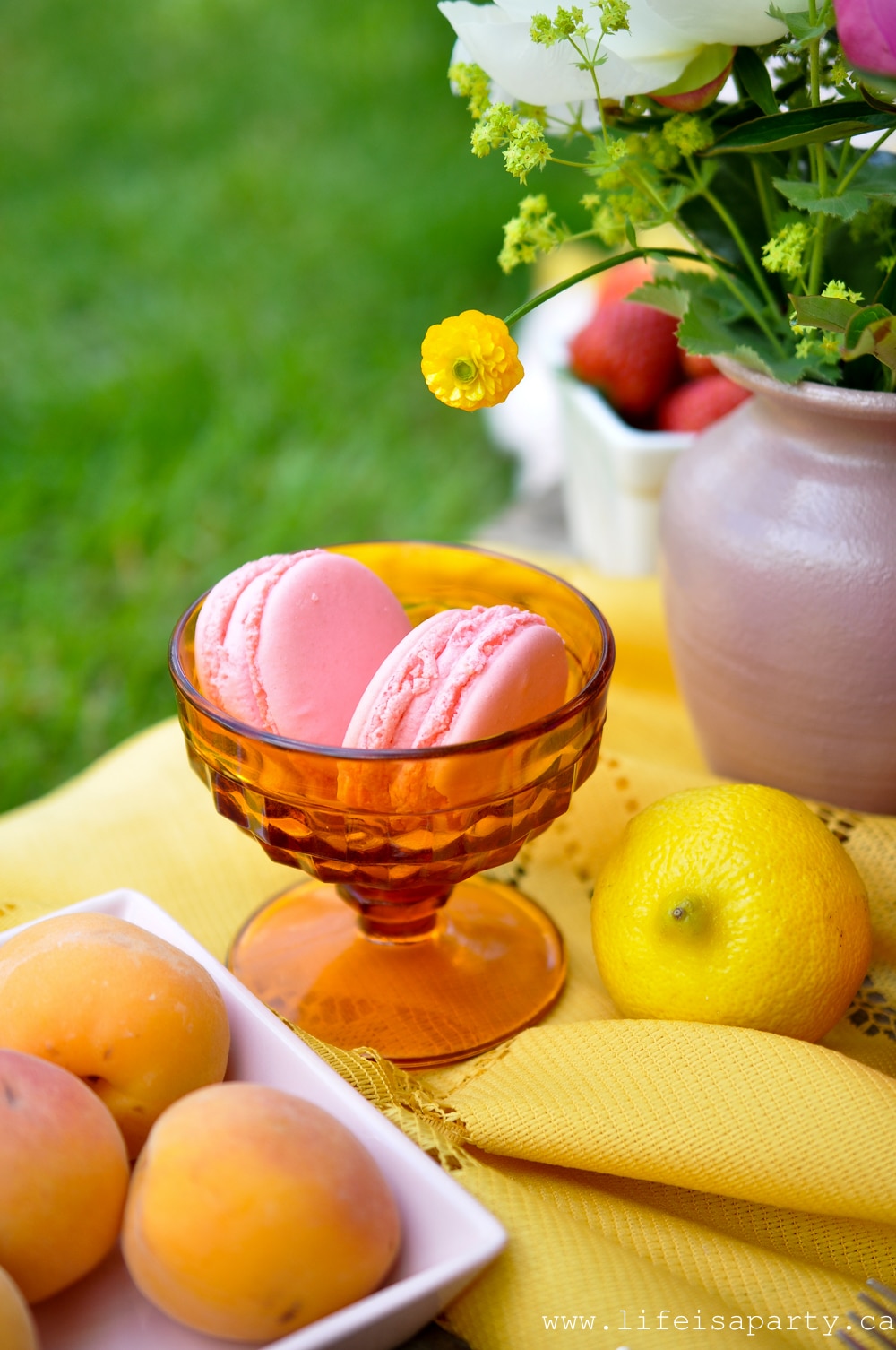 Pink macaroons in a amber glass dessert bowl.