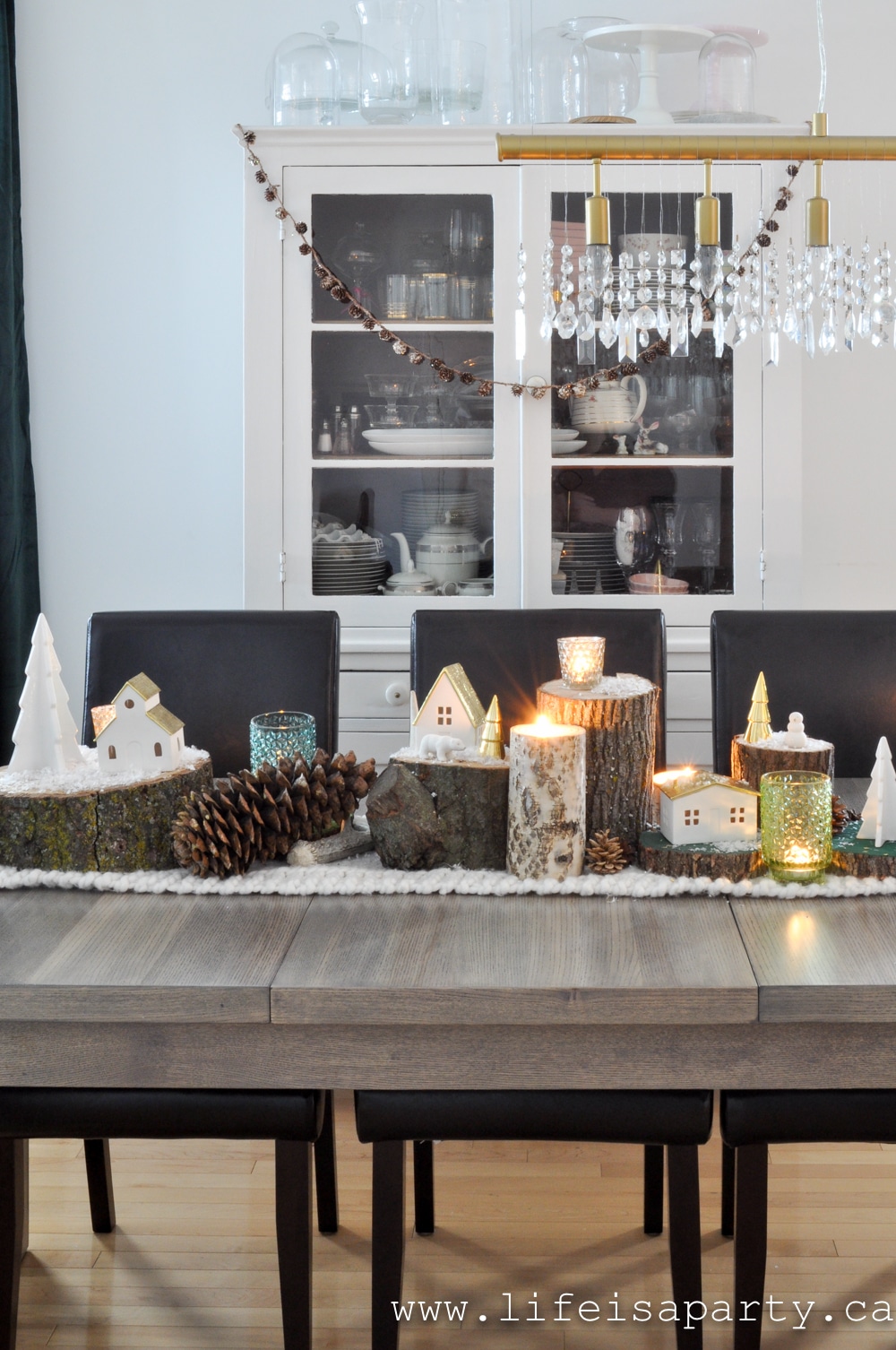 Christmas table scape with wood logs and candles and green decor