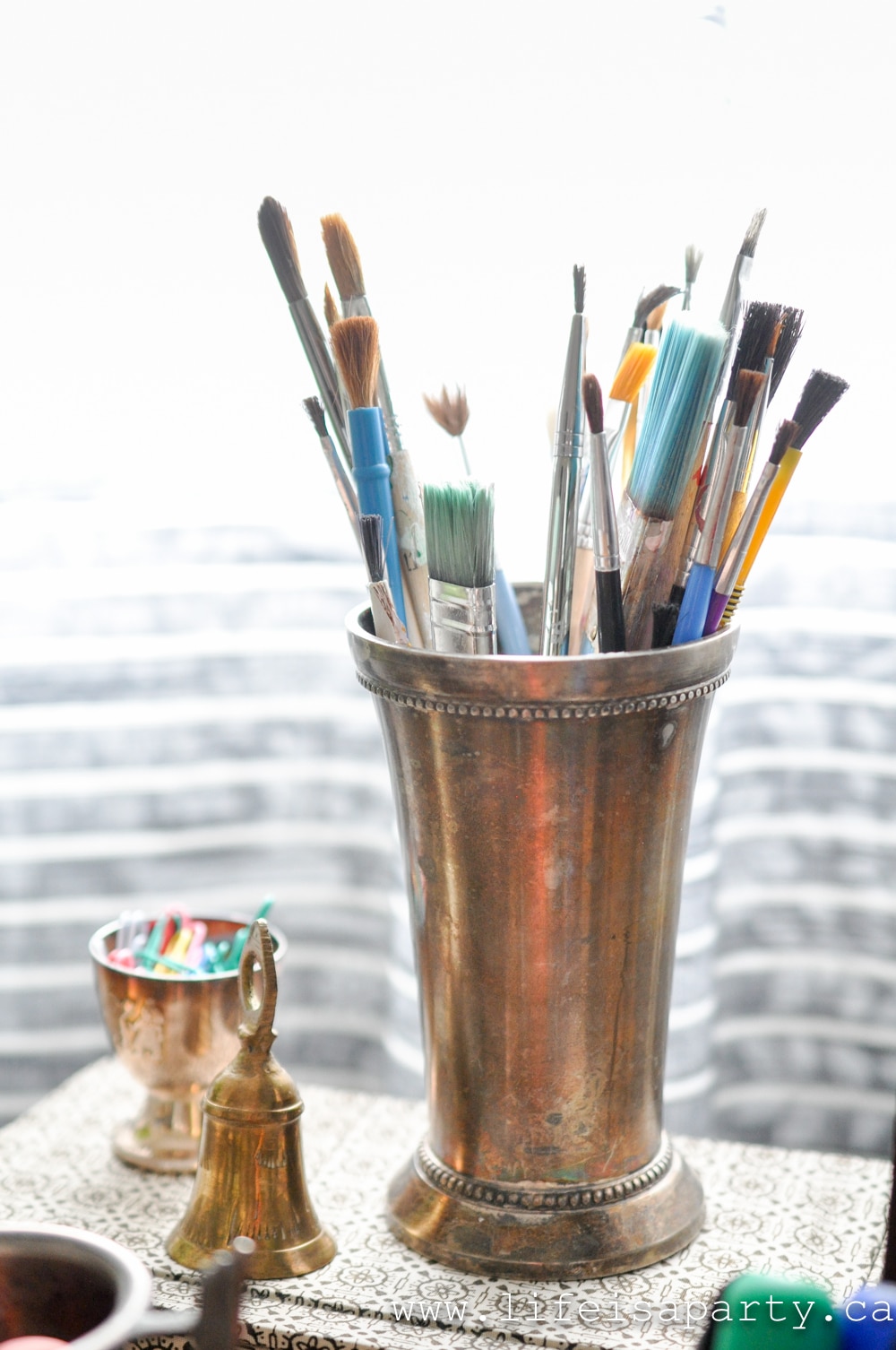 paint brushes in a vintage silver cup
