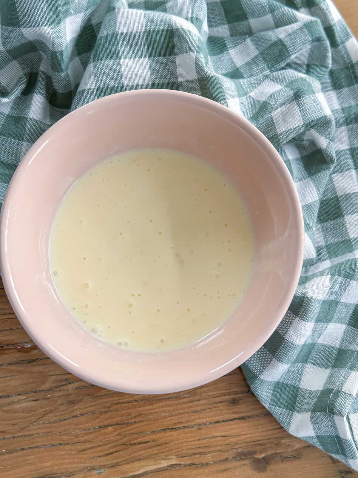 Egg and cream mixed in a small bowl ready to add to food processor scones.