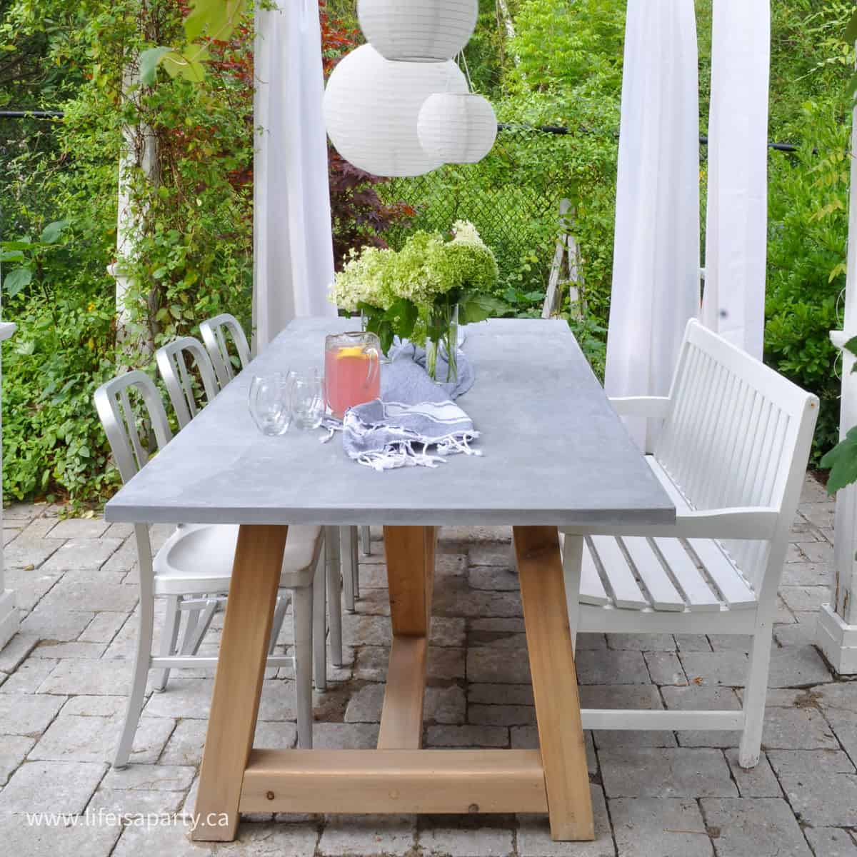 DIY Concrete Table in backyard with chairs and bench around it.