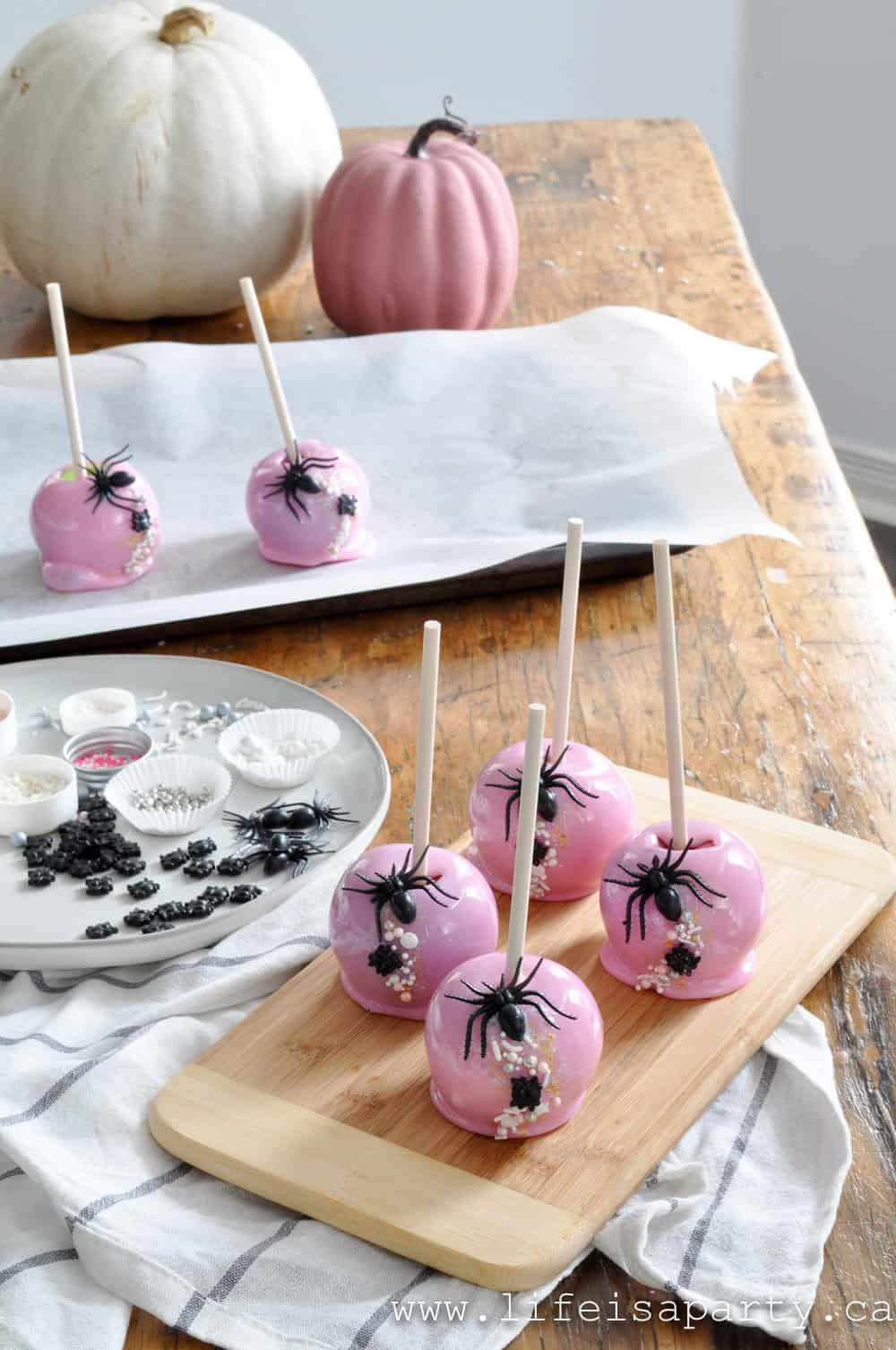 Making homemade pink candy apples and adding sprinkles for halloween.