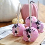 Homemade pink candy apples on a cutting board.