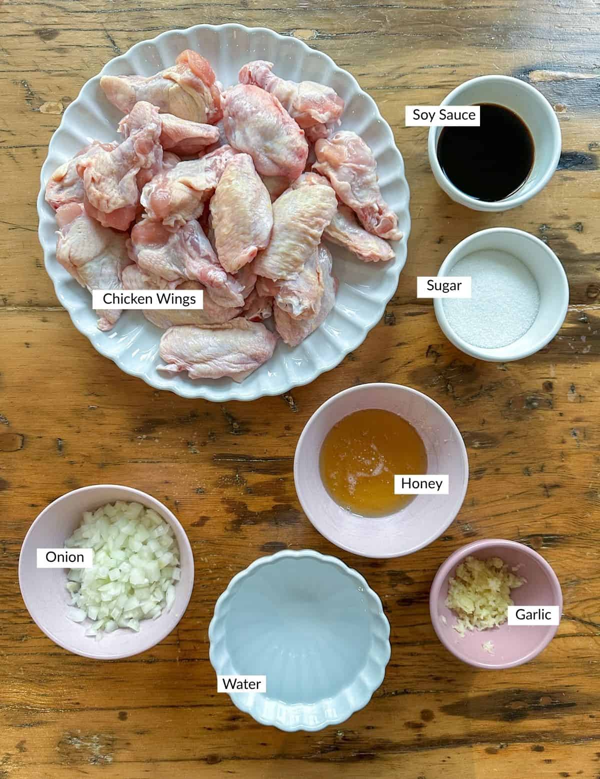 Easy homemade honey garlic chicken wing recipe ingredients in small bowls on a table.