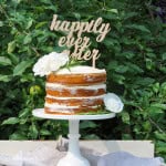 DIY wood cake topper on a naked cake with flowers.