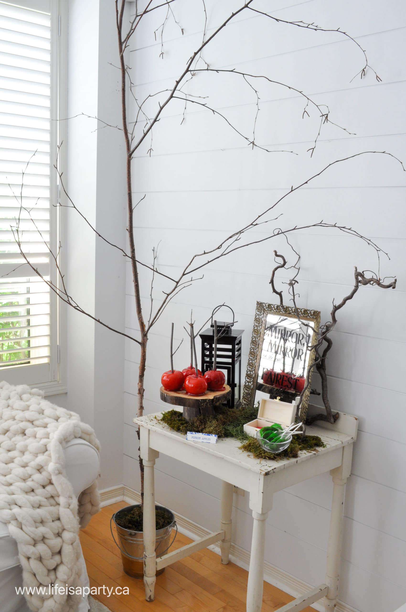 Snow White evil Queen themed party decor and food ideas, with tree branches, lantern, and poisin apples.