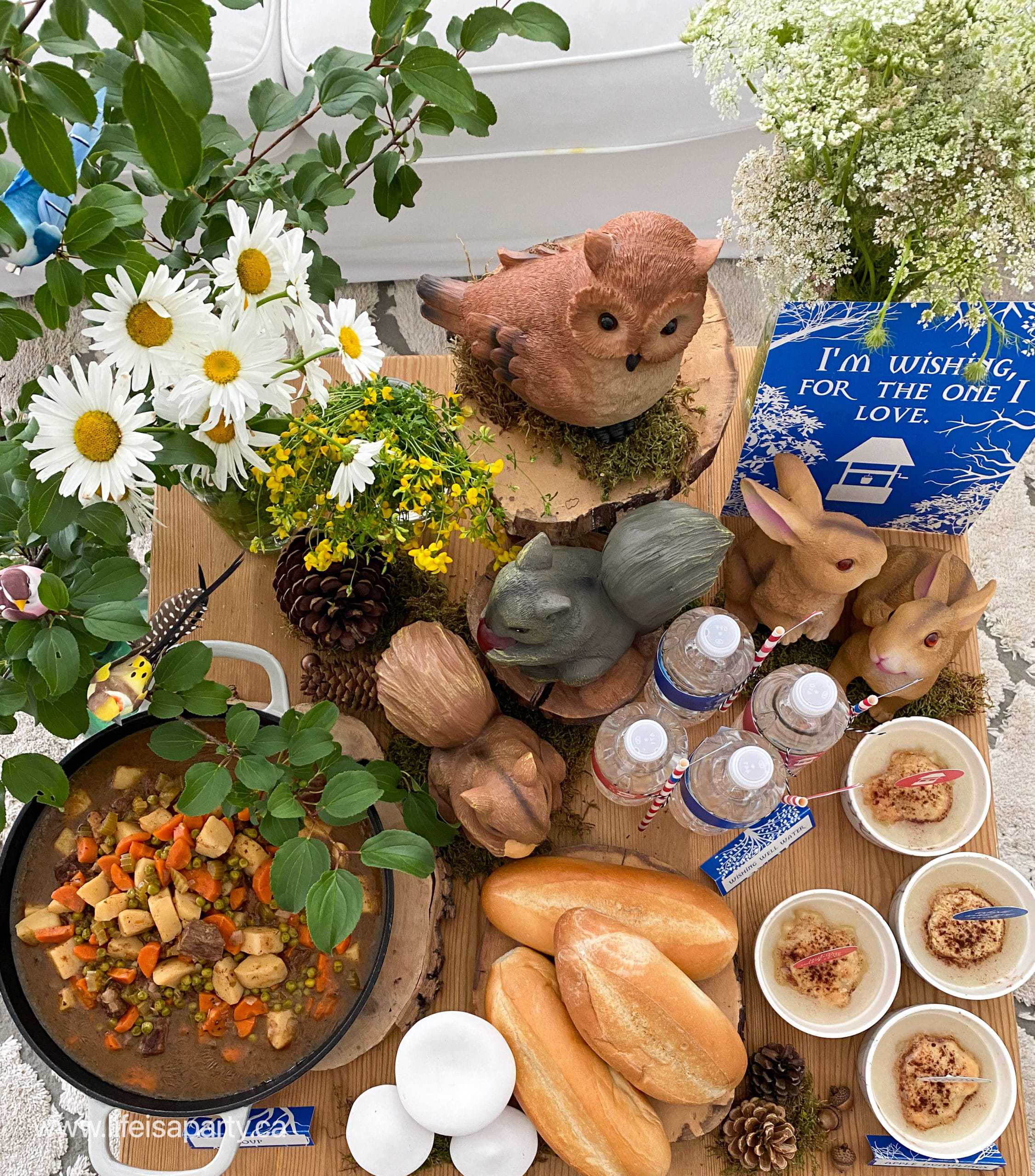 Snow White themed dinner of soup, bread, wishing well water, and apple dumplings on a table with wild flowers, mushrooms and faux animals.