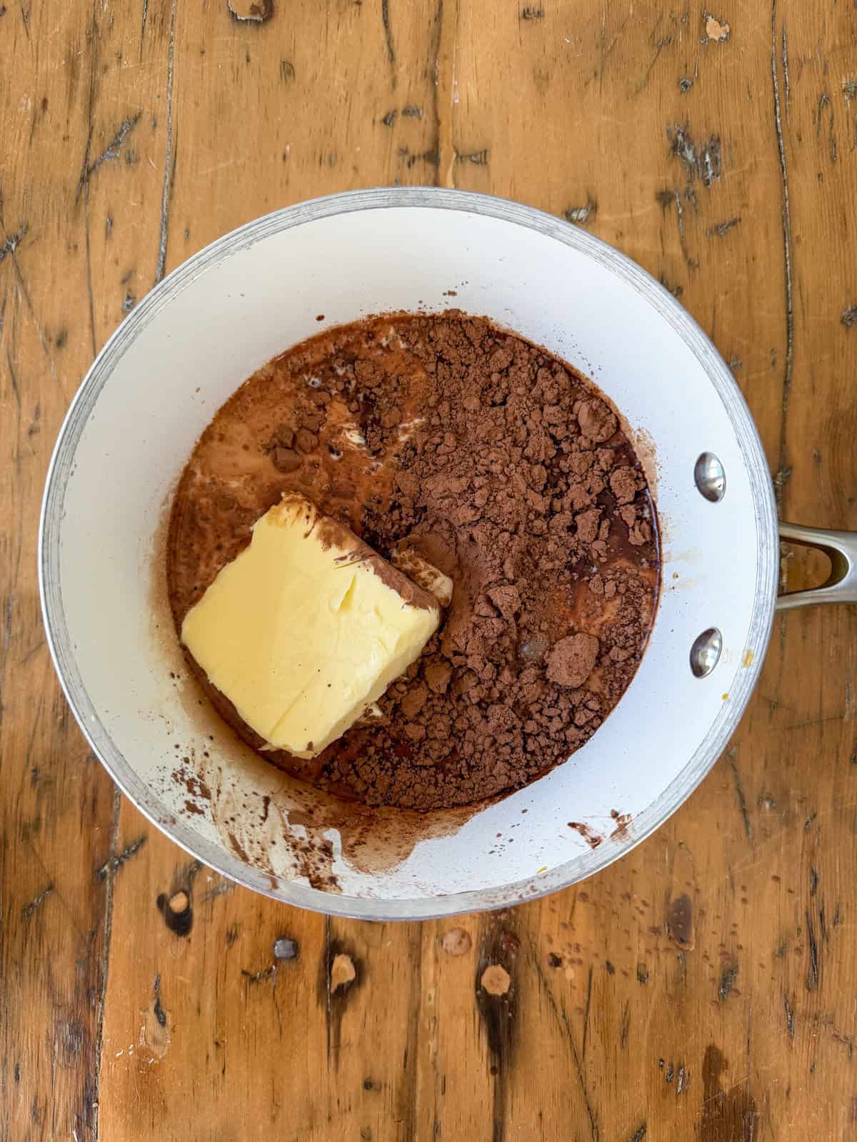 Butter and cocoa powder added to a white saucepan before making hot fudge sauce.