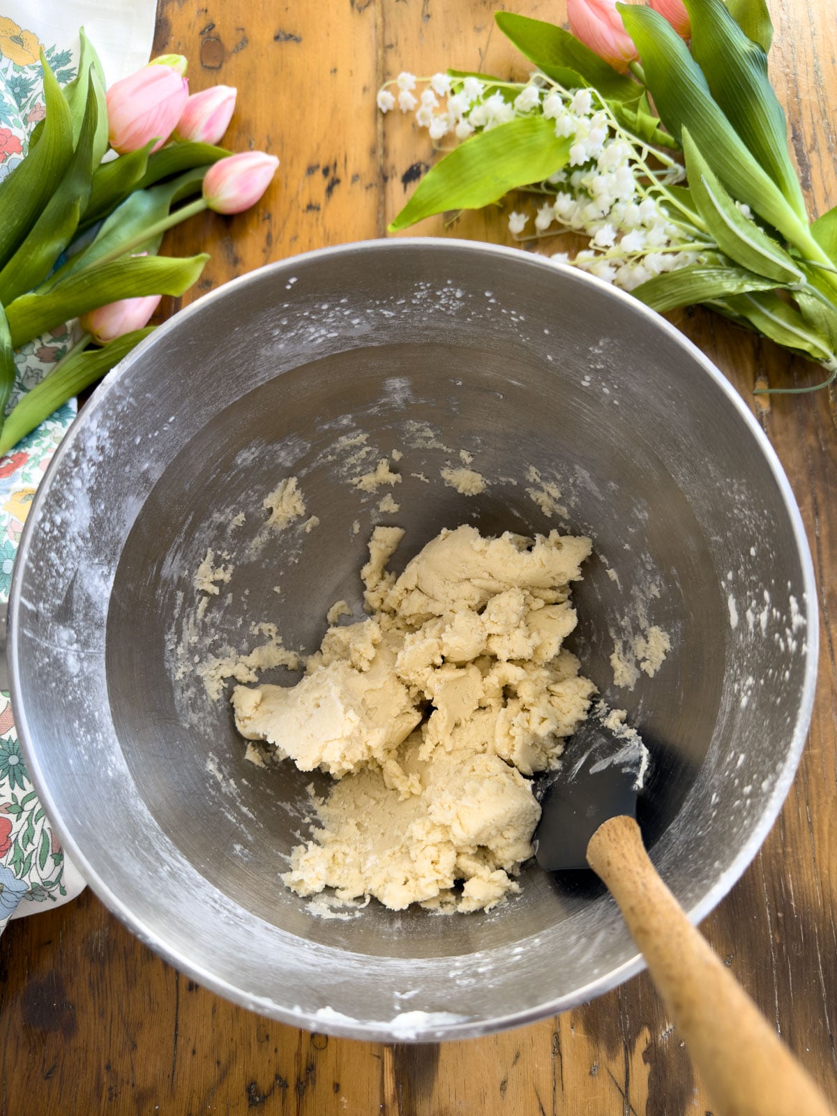Vanilla shortbread cookie dough formed in a stand mixer bowl with a spatula.