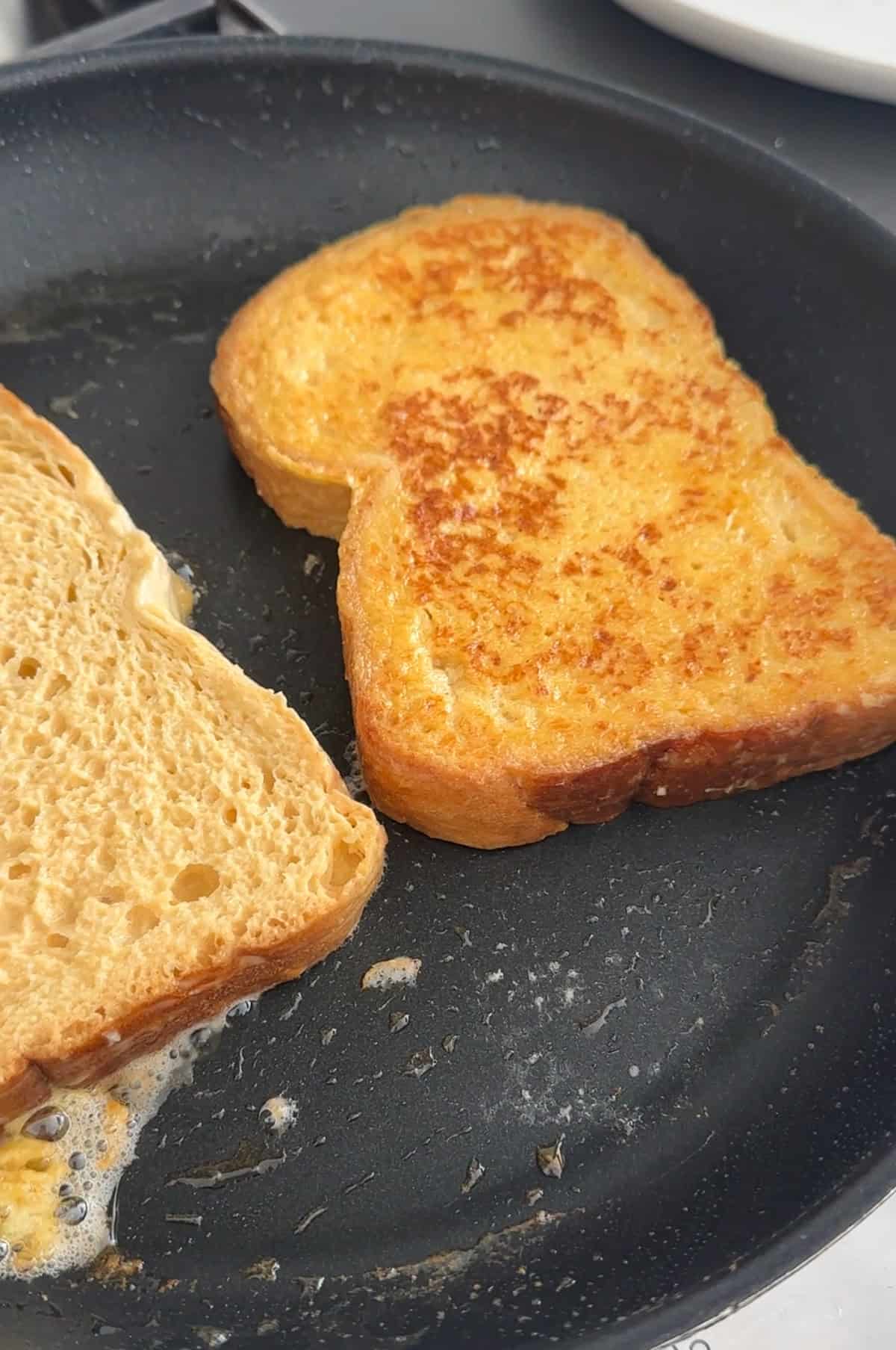Baileys French toast frying in a pan with butter.