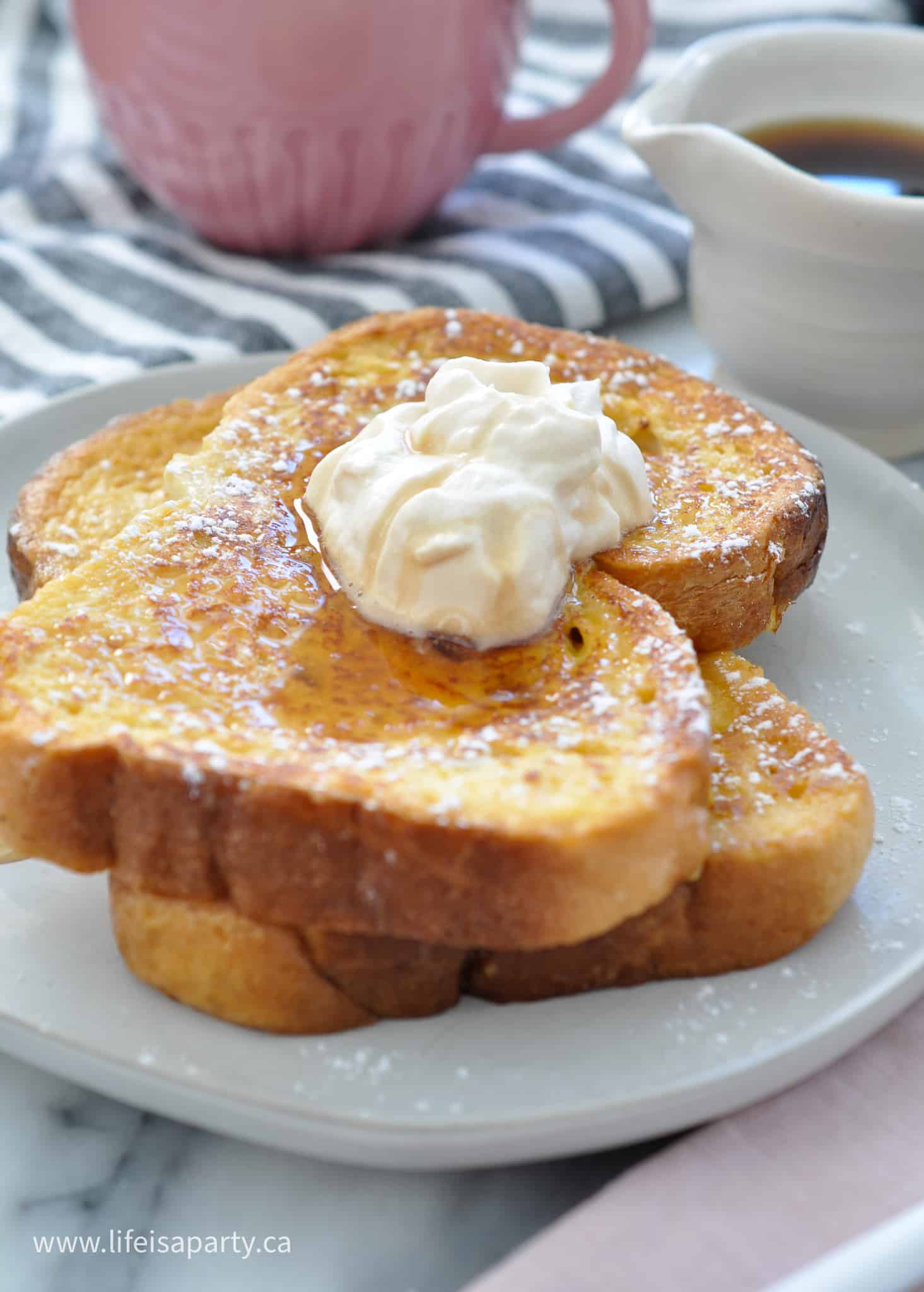 Two pieces of Baileys French toast on a plate with Baileys whipped cream and syrup.