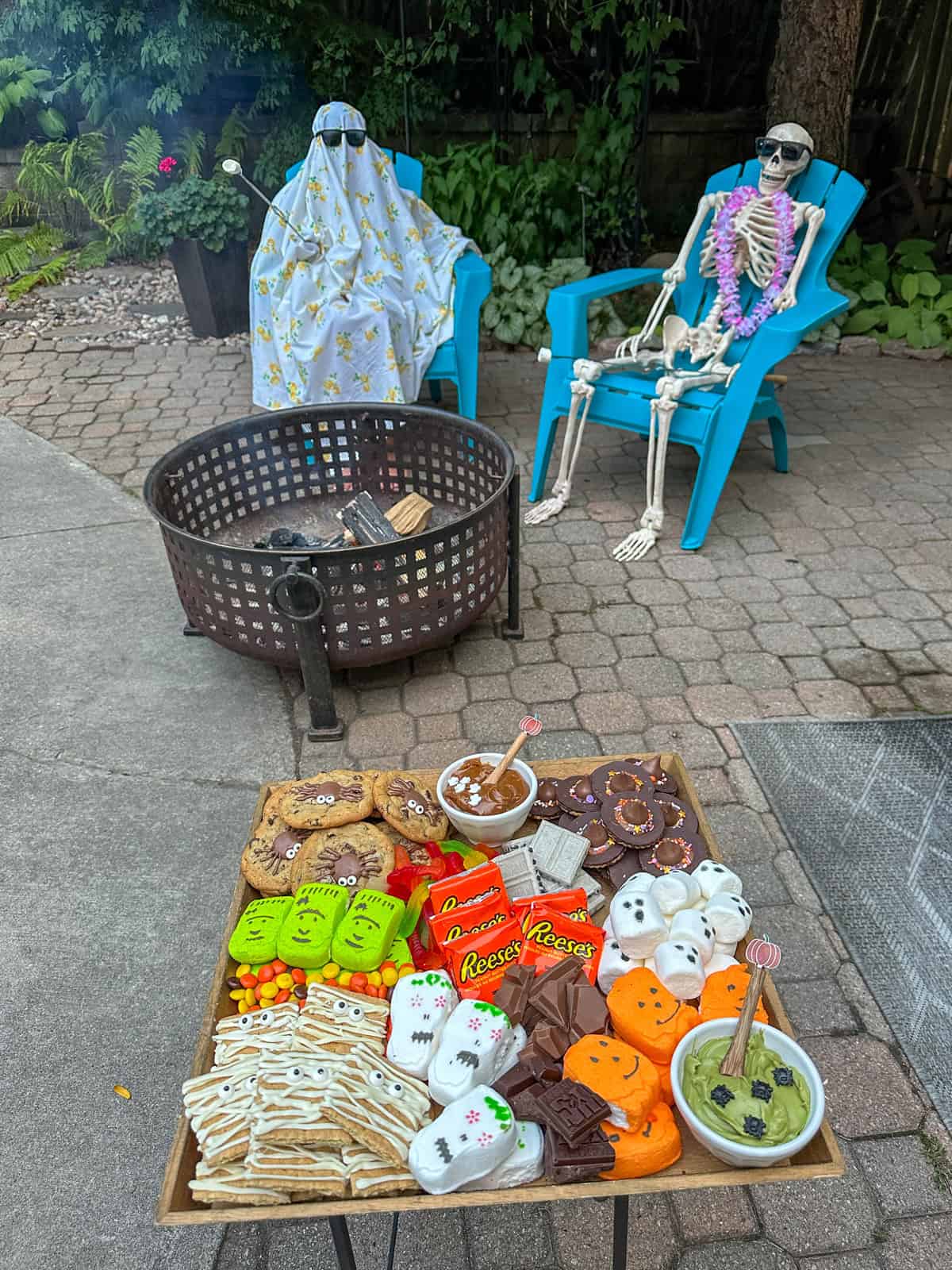 Ghost and skeleton roasting marshmallows over a fire for Halloween s'mores.