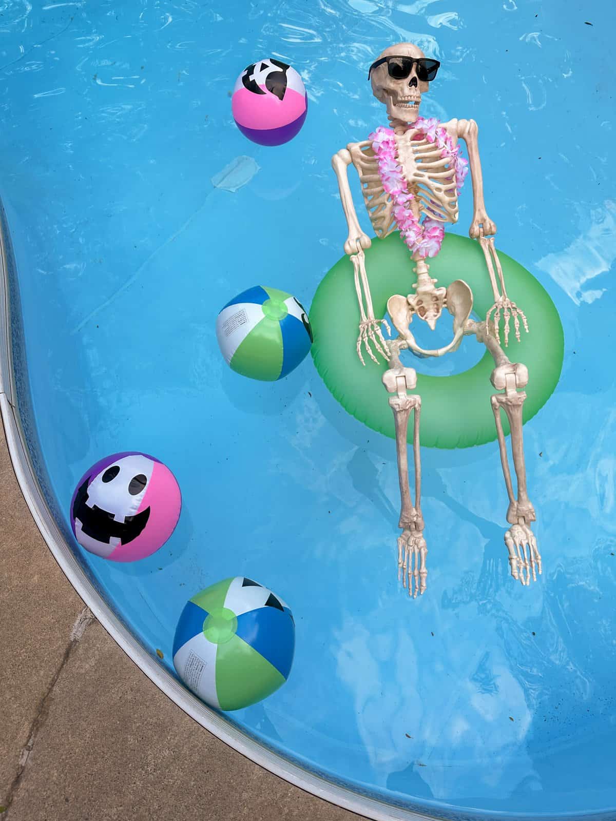DIY Halloween beach balls and a skeleton in a floatie at a summerween party.