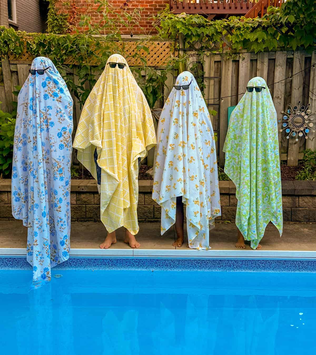 Summerween party with ghosts in colorful vintage floral sheets and sun glasses.